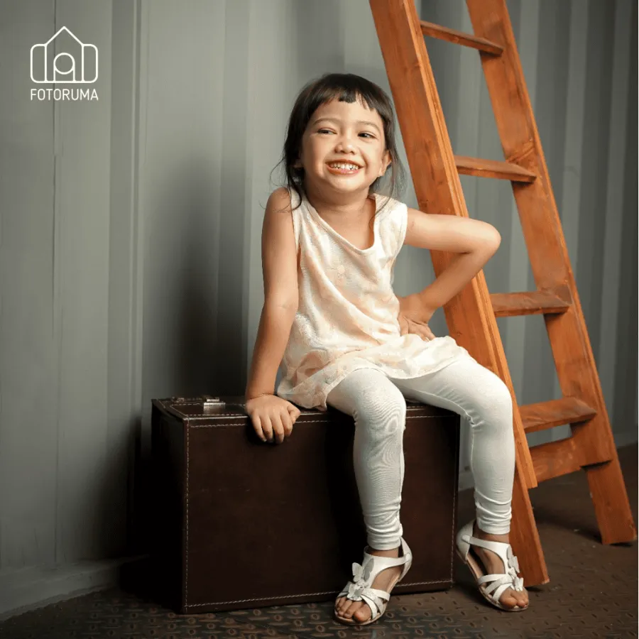 Foto kids portfolio anak perempuan dengan properti koper dan tangga kayu